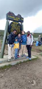 Family outside Shira Base Camp sign hiking one day to Shira Plateau on Mount Kilimanjaro